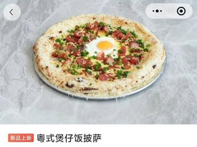 这是一张餐饮新品宣传类的截图，画面主体是放置在浅灰色大理石纹理台面上的创意披萨，该披萨为融合粤式煲仔饭元素的特色产品，饼底边缘蓬松烤至微焦，饼面铺有广式腊肠切片、切碎的葱花，中心位置还有一颗溏心煎蛋。画面下方配有红色背景的「新品上新」标识，旁边标注产品名「粤式煲仔饭披萨」，画面顶部带有移动端小程序样式的返回按钮与更多功能按钮，整体是商家用于推广创意新品餐品的内容。