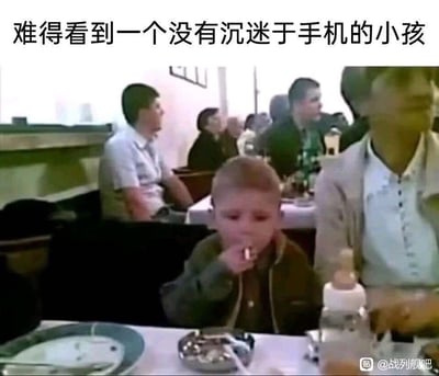这是一张餐厅场景的趣味梗图，画面上方配文“难得看到一个没有沉迷于手机的小孩”，而画面中心的小孩却正手持烟放在嘴边，桌上摆放着烟灰缸和奶瓶，形成强烈的反差感。
通过反讽的方式制造搞笑效果，讽刺比起沉迷手机，小孩出现了更不符合年龄的不良行为，引发观者对这种反差场景的调侃。