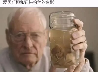 图片中一位白发老人（神似爱因斯坦）手持一个透明玻璃罐，罐内装有淡黄色液体和疑似固体的物体。图片上方配有文字“爱因斯坦和狂热粉丝的合影”，通过荒诞的方式暗示罐内为“狂热粉丝”，形成黑色幽默效果。
