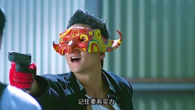 这张图是香港警匪电影《新警察故事》的剧照截图，画面中反派角色阿祖（关祖）戴着红黄配色带牛角造型的装饰性半脸面具，左手戴着红色手套持枪指向画面外的对象，嘴巴大张神态张狂嚣张，画面底部配有白色字幕“记住要有实力”，该场景属于电影中阿祖团伙作案的经典情节，和知名网络梗“阿祖收手吧”出自同一作品的相关剧情。
