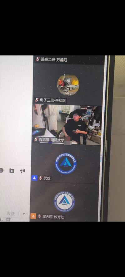 这是一张线上会议的屏幕截图，展示了多位参会者的界面：顶部是标注为「遥感二班-万睿阳」的参会者头像，接着是「电子三班-辛炳杰」的头像，随后是「袁志凯-同济大学」的视频画面——他身处杂乱的宿舍环境中，坐在椅子上手持手机，参与会议；下方还有「武晗」和「空天院-教育处」的机构标识头像。所有参会者的标识旁都带有静音图标，显示当前处于静音状态。图中没有双关、谐音梗或暗示类内容。