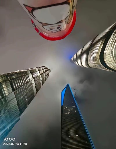 这是一张充满创意的合成仰拍图，以低角度仰拍上海陆家嘴的三座地标摩天大楼——上海中心大厦、上海环球金融中心、金茂大厦，同时将一个带有呆萌卡通形象的粉色奶茶杯合成到画面上方，利用视觉错位效果，让奶茶杯看起来像是第四座“摩天高楼”，与真实的三座大厦形成趣味满满的“陆家嘴新四件套”，画面反差感拉满，充满幽默感。