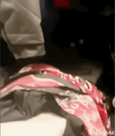 这是一段动态GIF，画面左侧露出一个人的下半身（仅腿部），画面下方一块带有红白色花纹的布料/包状物体在持续蠕动，看起来像是有活物在其中活动，画面构图较为混乱，整体氛围滑稽，能给人带来搞笑、疑惑的观感，没有包含双关、谐音梗等内容。