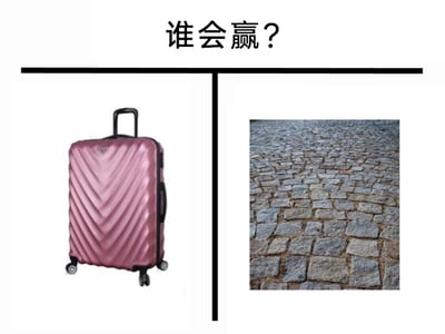 这是一张左右对比的图文混排静态梗图，顶部居中位置配有黑色文字“谁会赢？”，画面被一条黑色竖线分为左右两部分：左侧是一个粉色、带有V形纹路的四轮拉杆行李箱，右侧是一块由不规则石块铺成的凹凸不平的石板路面。这张图玩的是生活场景的趣味梗，因为行李箱的滚轮在石板路上推行时会非常颠簸，不仅推行费力，还可能损坏行李箱滚轮，所以实际上石板路会“赢”，用来调侃人们在不平整路面推行李箱的糟糕体验。