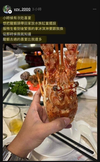 社交媒体用户yzy_2000分享的童年趣事图文。图片中一只手正拿着一个煮熟的龙虾头，背景是摆满菜肴的喜宴餐桌，有香菇、蔬菜、汤碗等餐具。配文讲述小时候吃喜宴时，想把龙虾头带回家放进鱼缸当摆设，被服务员紧张地用冰淇淋换走，由此幽默地得出“龙虾去过的喜宴比我还多”的结论，充满生活气息和童趣。