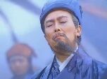 图片中是一位头戴蓝色头巾、身着蓝色长袍的男子，表情严肃，背景有雾气，隐约可见其他人物轮廓，整体呈现出庄重的历史剧氛围。