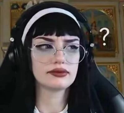这是一张直播画面截图，图中是一位有着黑色齐刘海长发的女性，她戴着白色发箍，搭配黑色的类似修女服饰的装扮，头戴大尺寸黑色耳机，脸上戴着细框眼镜，眉头微皱，眼神斜向上，嘴角下撇，露出明显的疑惑、不解的神情，在她头部右侧还有一个白色的问号符号，进一步强化了这种困惑的情绪，这张图常被用作表达疑惑、不解情绪的表情素材。