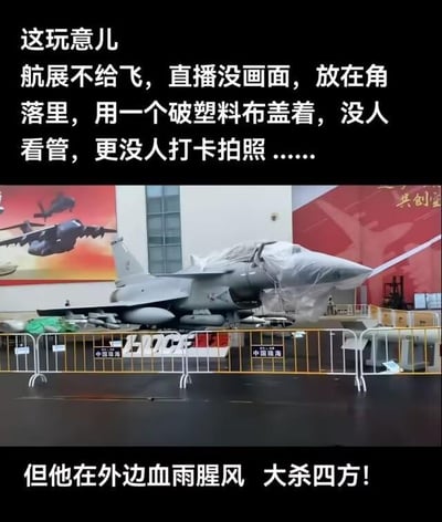 这是一张图文混排的内容，画面主体是一架F-16战机，它被塑料布盖住机头，放置在航展场馆的角落，周围用印有“中国珠海”字样的围栏隔开，现场显得冷清无人关注。图中配文分为两部分，先描述这架战机在航展上的尴尬处境：“这玩意儿 航展不给飞，直播没画面，放在角落里，用一个破塑料布盖着，没人看管，更没人打卡拍照……”，随后话锋一转：“但他在外边血雨腥风 大杀四方！”，通过强烈的反差感，调侃这架战机在实战场景中表现活跃，却在航展上无人问津的状况。