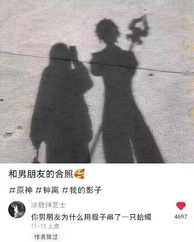图片展示了一张社交媒体帖子，内容为地面上的两个影子：左侧影子似一人正在用手机拍照，右侧影子则酷似游戏《原神》中的角色钟离，手持长枪。图片上方文字为“和男朋友的合照😊”，并带有#原神 #钟离 #我的影子 标签。下方有用户“冰糖拌芝士”的评论：“你男朋友为什么用棍子串了一只蛤蟆”，获4697个赞，且标注“作者赞过”，发布地点为上海，时间11-15。整体通过影子创意模仿游戏角色，营造幽默的“情侣合照”效果。