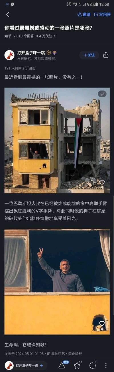 这是一张知乎回答的截图，回答的问题是“你看过最震撼或感动的一张照片是哪张？”。回答中展示了两张关联照片：第一张是一栋在战火中被炸得只剩一半的居民楼，其中一侧的黄色建筑结构尚存，一位巴勒斯坦大叔在该建筑的窗口举起手，比出象征胜利的V字手势，楼房的废墟区域悬挂着巴勒斯坦国旗；第二张是大叔的特写，能清晰看到他平静且坚毅的神情，同时在黄色建筑的墙洞处，有一只狗探出头，显得十分放松。回答的配文描述了这个场景，并发出“生命啊，它璀璨如歌！”的感叹，传递出在战争带来的破败环境中，人们依然保持的乐观精神与对生命的热爱，极具感染力。