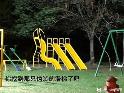 这是一张夜晚户外游乐场的趣味图片，画面中包含黄色滑梯、绿色跷跷板、秋千等多种游乐设施，配文“你找到那只伪装的滑梯了吗”引导观者观察。其中最左侧的“滑梯”并非真实的游乐设施，而是由两个人配合摆出的造型，模仿滑梯的黄色外观与弯曲形态，和旁边的真实滑梯放在一起形成了视觉错位，极易让人混淆，以此制造出考验观者观察力的趣味效果。