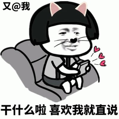 图片中是一个卡通风格的角色，有着黑色齐耳短发和粉色猫耳，正坐在灰色沙发上，双手捧着一部智能手机。角色面部带有微笑表情，手机旁有三颗粉色爱心图案飘出。图片左上角有文字“又@我”，底部有文字“干什么啦 喜欢我就直说”。整体呈现出一种俏皮又略带无奈的幽默氛围，常用于调侃在社交场合中被频繁@的情景，暗示对方可能对自己有好感。