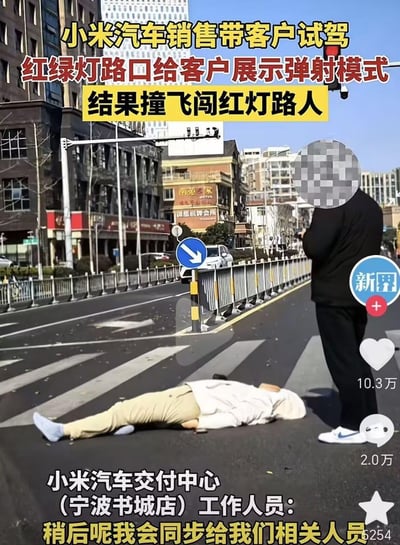 这是一张城市路口交通事故的视频截图，画面中一名路人倒在人行横道上，旁边站立着一名面部打码的黑衣男子。配文信息显示，该事故是小米汽车销售带客户试驾时，在红绿灯路口为客户展示车辆弹射模式，意外撞飞了闯红灯的路人；下方还有小米汽车交付中心（宁波书城店）工作人员的回应，表示会将情况同步给相关人员。现场为城市街道，背景可见商铺、交通护栏与交通标识，画面带有短视频平台的互动元素，点赞量达10.3万，评论量2.0万。