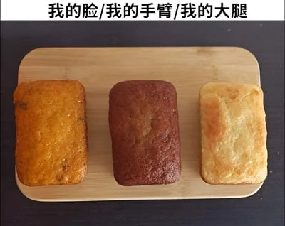 图片中展示了一块木质托盘上并排放置的三块长方形糕点，从左到右分别呈现金黄色、深棕色和浅黄色，表面均有烤制后的光泽。托盘上方配有文字“我的脸/我的手臂/我的大腿”，通过不同颜色和质感的糕点幽默类比人体不同部位的状态差异，可能暗含对皮肤色调或质感的自嘲式调侃。