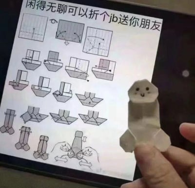 这张图展示了一个趣味恶搞折纸的反差效果：设备屏幕上显示着标题为“闲得无聊可以折个jb送你朋友”的折纸教程，步骤详细；而实际折出的成品被手绘上了圆圆的眼睛和微笑的嘴巴，造型软萌可爱，和教程标题的预期形成强烈的搞笑反差。一只手正捏着这个成品折纸，将其展示在教程屏幕前，整体内容充满恶搞趣味，适合闲暇时间用来整蛊朋友、打发时间。