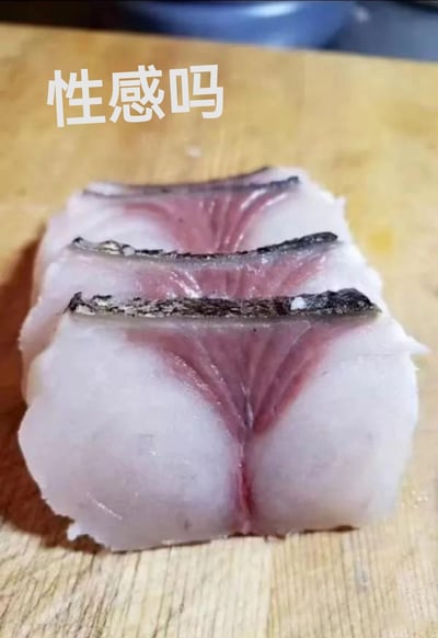 这张图是一块鱼肉横切片，被巧妙地放置后从视觉上看上去很像人的臀部。上方配有大字“性感吗”，形成强烈的视觉反差和双关笑点。图像本身没有任何实际情色内容，但通过摆拍和配字制造出一种幽默的“错位性感”，常被用于网络调侃和评论区的“擦边”玩笑。

图中有明显的双关与错觉幽默，通过食物与人体局部形似调侃“性感”这一概念，但实际内容健康。