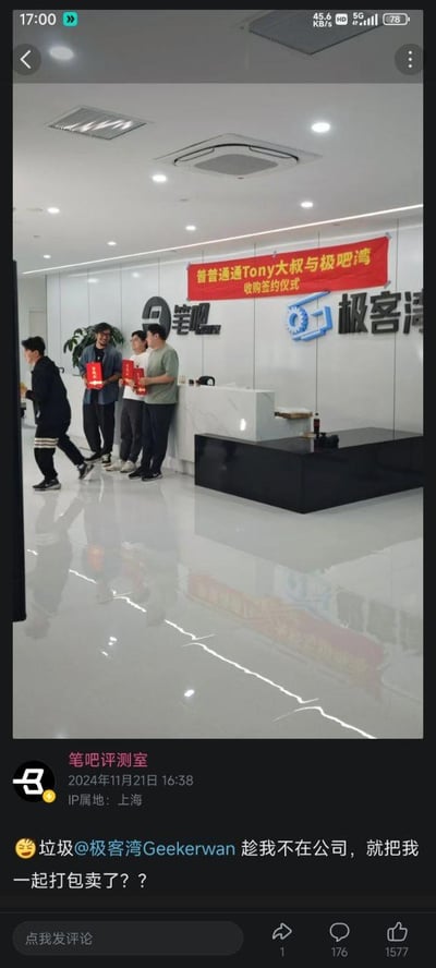 这是一张社交平台动态截图，发布者为数码科技领域的笔吧评测室。配图展示了笔吧与极客湾的联合办公前台区域，墙面悬挂着一条红色横幅，上面写有“普普通通Tony大叔与极吧湾收购签约仪式”的字样，三位工作人员手持红色文件站在前台旁，另有一人做出被“打包带走”的夸张动作，营造出被收购的趣味场景。动态文案为“垃圾@极客湾Geekerwan 趁我不在公司，就把我一起打包卖了？？”，整体是两大数码内容账号的趣味玩梗互动，以模拟商业收购的场景制造搞笑效果，充满调侃意味，在数码爱好者圈子里引发了趣味讨论。
