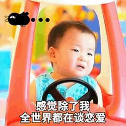 图片中是一个坐在红色玩具车里的宝宝，穿着蓝色上衣，正握着方向盘。宝宝表情略带委屈，眼神看向一侧。左上角有一个黑色的卡通小角色，旁边有三个点。图片底部配有文字：“感觉除了我全世界都在谈恋爱”，整体营造出一种单身人士面对周围都在恋爱的无奈又搞笑的氛围。