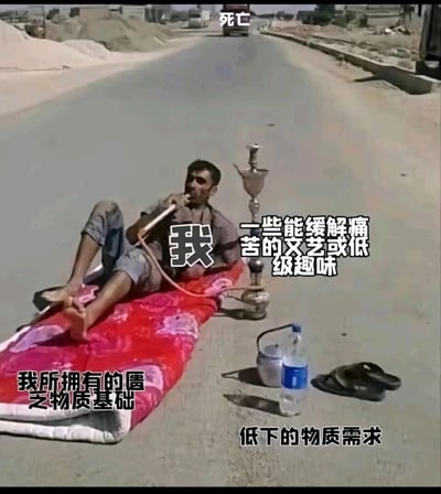 这是一张带有自嘲性质的网络梗图，画面取材于真实的生活场景：一名男子躺在道路中间的红色薄褥上抽水烟，周围只有简单的饮水容器和拖鞋，物质条件十分匮乏。图片通过添加中文注解，将男子标注为“我”，把他简陋的铺盖定义为“我所拥有的匮乏物质基础”，水烟标注为“一些能缓解痛苦的文艺或低级趣味”，旁边的饮水和拖鞋标注为“低下的物质需求”，道路远处的车辆标注为“死亡”，以此自嘲式地描绘出人们在面对匮乏的物质条件、生活的压力甚至绝境时，只能依靠简单的事物来麻痹自己、缓解痛苦，以躺平的姿态直面困境的无奈心态，容易引发在生活压力下的群体共鸣。