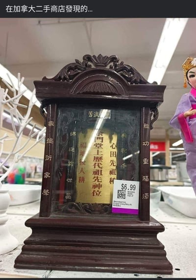 图片展示了在加拿大一家二手商店中发现的中国传统祖先神位。这个深色木质神位做工精致，带有雕刻花纹，内部有金色牌位，上面写有"余门堂上歷代祖先神位"等传统祭祀文字。神位被当作普通商品标价6.99美元出售，旁边还摆放着一个传统服饰的人偶。这种将具有重要文化和宗教意义的物品当作普通二手商品出售的场景，形成了强烈的文化反差和视觉冲击。