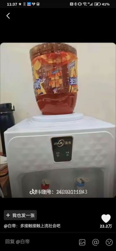 这是一张抖音平台的内容截图，画面主体为一台白色浪木品牌的立式饮水机，常规放置桶装纯净水的位置被替换成了一桶大容量的瓶装冰红茶饮料，画面下方显示用户“白帝”发布的评论“多接触接触上流社会吧”，该评论收获22.2万点赞，同时界面还显示了抖音号水印、点赞按钮、回复输入框等抖音APP的交互元素，整体用夸张的调侃将普通人的脑洞生活操作冠以“上流社会”的名头，形成搞笑反差的玩梗效果。