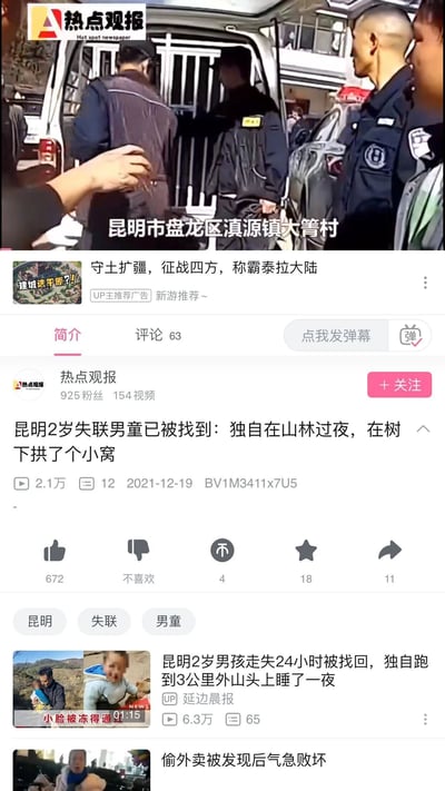 这是一张哔哩哔哩（B站）平台的新闻视频页面竖屏截图，顶部是视频播放画面，显示昆明市盘龙区滇源镇大箐村的现场场景，有警务人员和相关人员，还有带铁栏的工作车辆，画面标注了地点；页面中间是视频的核心信息，发布账号为“热点观报”，该账号有925粉丝、154个视频，此视频标题为“昆明2岁失联男童已被找到：独自在山林过夜，在树下拱了个小窝”，播放量2.1万，发布于2021年12月19日；页面下方展示了相关推荐视频，其中一条是“延边晨报”发布的同事件视频，标题为“昆明2岁男孩走失24小时被找回，独自跑到3公里外山头上睡了一夜”，播放量6.3万，整体内容围绕昆明2岁失联男童成功找回的社会新闻展开。