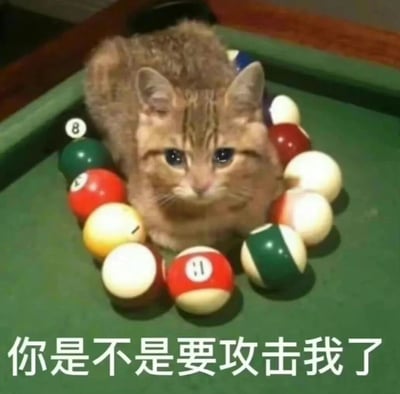 一只橘猫被彩色台球围绕着坐在绿色台球桌上，猫咪表情看起来有些担忧和无辜，眼睛睁得很大直视前方。图片底部有文字："你是不是要攻击我了"，通过猫咪的表情和文字形成幽默效果，仿佛猫咪真的在担心被台球或打台球的人攻击。