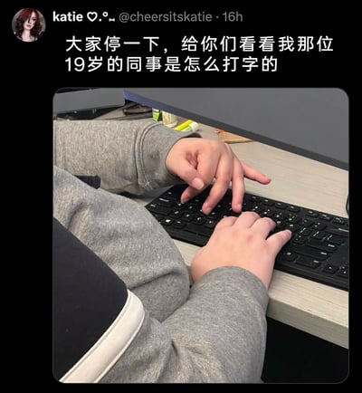 这是一张X平台（原Twitter）的社交媒体截图，用户katie分享了自己19岁同事的奇特打字姿势。画面中，这位穿着灰色卫衣的同事采用了非常不符合常规打字指法的方式：左手仅伸出三根手指，右手仅用一根手指来敲击键盘按键，这种怪异又滑稽的打字姿势成为了画面的焦点，展现了职场中有趣的小细节，引发人们对不同人打字习惯的关注。