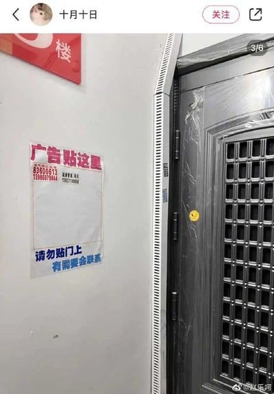 这是一张在居民楼楼道内拍摄的实拍图，画面右侧是一扇还包裹着保护膜的入户门，左侧墙面上贴着一张手写告示：上方用醒目的红色字体标注“广告贴这里”，附带了疏通管道、钻孔的联系电话，底部用蓝色字体提醒“请勿贴门上 有需要会联系”，旁边墙面还有红色的“楼”字标识。住户通过这种方式，为楼道小广告划定了专门的张贴区域，既避免自家门被乱贴，也方便有需求的人联系相关服务，是应对楼道小广告的实用又贴心的办法。