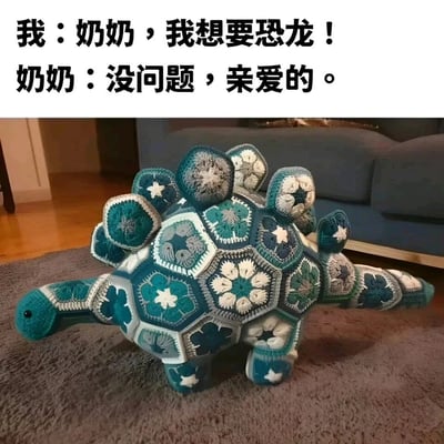 这是一张充满温情的梗图，上方配有对话文字：孩子向奶奶表达想要恐龙的愿望，奶奶爽快答应；下方展示了奶奶的成品——一只由蓝灰系多种钩针拼花片缝合而成的剑龙玩偶。玩偶造型还原剑龙的形态，每一片花片都有独特的花纹，精致的手工制品既满足了孩子的愿望，也满含奶奶的疼爱，传递出手工创作的温暖与治愈感。