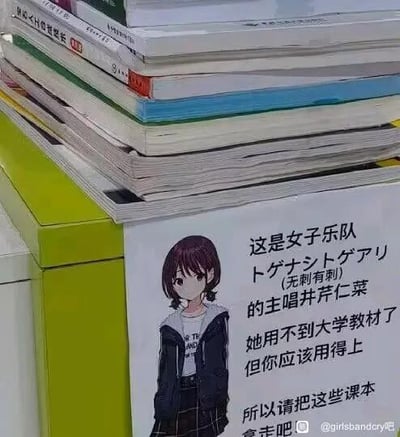 图片中展示了一摞堆叠的大学教材，放置在绿色的柜子上。柜子侧面贴有一张带有动漫风格女孩的贴纸，女孩有着棕色短发和齐刘海，穿着黑色外套和白色内搭，表情平静。贴纸上的文字写道：“这是女子乐队トゲナシトゲアリ (无刺有刺) 的主唱井芹仁菜 她用不到大学教材了 但你应该用得上 所以请把这些课本拿走吧”，右下角有水印“@girlsbandcry吧”。整体画面通过真实的教材与虚构的动漫角色结合，以幽默轻松的方式鼓励有需要的人取走教材。