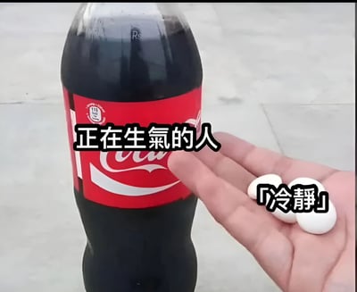图片中展示了一瓶可口可乐，瓶身上有红色标签，标签前方叠加文字“正在生气的人”。画面右侧有一只手摊开，掌心放着三颗白色圆形药片，药片上方配有文字“「冷静」”。整体通过将可口可乐拟人化为“正在生气的人”，并以手中的“冷静”药片形成对比，营造出一种试图用简单方式安抚愤怒情绪的幽默效果。