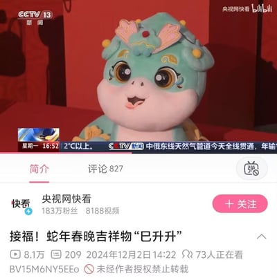 这是B站平台上央视网快看发布的视频截图，展示了2025年蛇年春晚的吉祥物“巳升升”，它是一只青绿色的卡通蛇形象，造型圆润可爱，表情开心兴奋。画面上方带有央视新闻的滚动字幕，播报中俄东线天然气管道全线贯通的新闻；下方是B站视频的界面信息，显示该视频标题为《接福！蛇年春晚吉祥物“巳升升”》，发布于2024年12月2日，拥有8.1万播放量和827条评论。吉祥物“巳升升”的名字对应蛇年地支“巳”，寓意步步高升，传递新春祝福。
