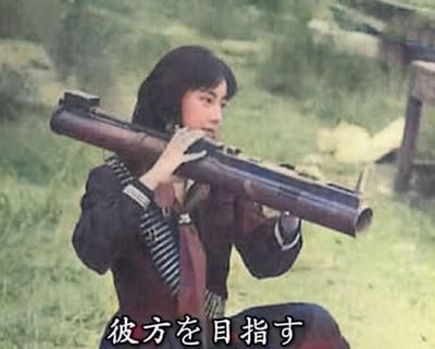 这是一张利用视觉错位效果的创意改图，图中的女生原本手持管乐器，通过与背景物体的巧妙重合，看起来像是扛着一枚火箭筒（RPG），女生神情专注，做出瞄准的姿态。图下方配有日文“彼方を目指す”，翻译为中文是“向着远方”，让原本文艺的场景瞬间充满硬核热血的反差感，制造出搞笑的效果，图中没有双关、谐音梗或暗示内容。