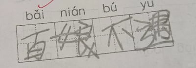 这是一张小学低年级语文写字作业的静态扫描图，属于图文混排的田字格书写练习内容。上方标注了拼音“bǎi nián bú yù”，要求学生写出对应的汉字，但学生在田字格中错误地将“百年不遇”写成了“百娘不遇”，其中“年”被错写为“娘”，“遇”的书写也十分潦草且结构错误，作业左上角还有一个红色的批改标记指向第一个拼音，整体字迹潦草，田字格的辅助虚线清晰可见，呈现出典型的低年级学生汉字书写错误的作业状态。