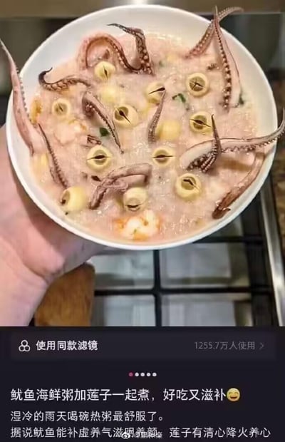 这是一张来自抖音平台的趣味P图截图，画面上方是一只手端着的一碗粥状食物，其中的鱿鱼须和被特效滤镜处理成“莲子”模样的通心粉排列在一起，视觉上形成类似奇怪生物的错觉，让人乍一看以为是加了莲子的鱿鱼海鲜粥；画面下方是抖音的内容发布界面，显示“使用同款滤镜”按钮，已有1255.7万人使用该滤镜，配文一本正经地介绍这道“粥品”的滋补功效，称湿冷雨天喝热粥很舒服，还科普了鱿鱼和莲子的养生作用，但实际上这是利用滤镜制造的视觉玩笑，将普通的通心粉和鱿鱼须伪装成“莲子鱿鱼粥”，通过一本正经的介绍和虚假的视觉效果形成反差，制造搞笑氛围。